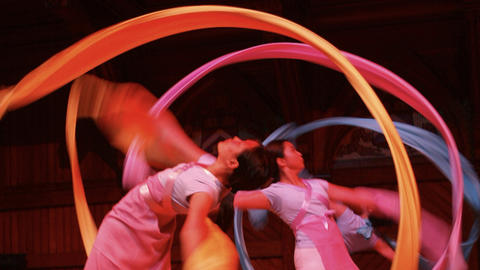 hree people dressed in Chinese clothing performing a dance with colored ribbons