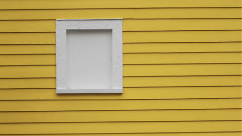A yellow exterior wall with a window with the frame and glass painted white