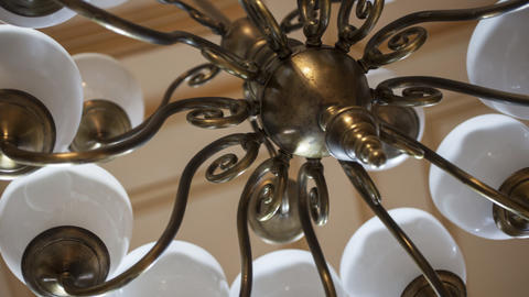 Closeup of brass chandelier with white globes, viewed from below