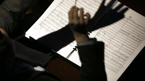 Close-up of conductor’s hands and a musical score.