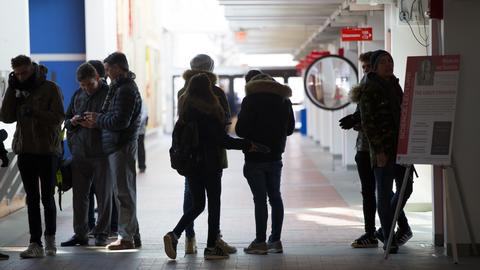 View of a hallway with a group of jacketed people in the foreground waiting in a line.