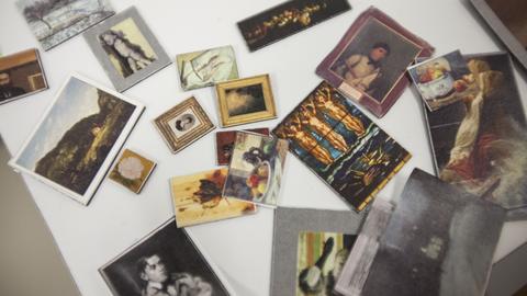 Table top arrayed with miniature models of a variety of artworks. 