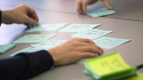Closeup of hands organizing post-its on a tabletop.