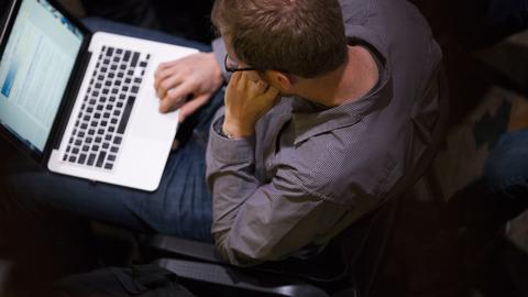 Overhead view of seated person working with a laptop on their lap.