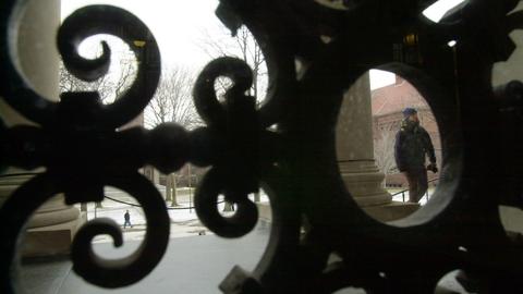 Closeup of filigree on a gate with columns and a plaza beyond.