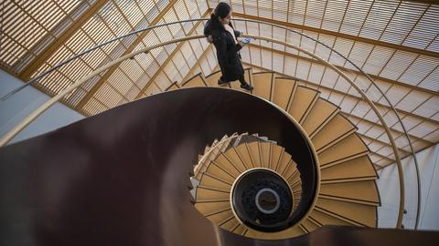 View from above of a person descending a spiral staircase.