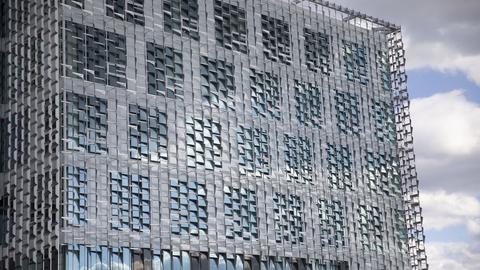 A modern building with a grid-like facade of metallic panels and glass windows. 