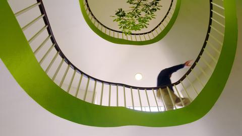 View from below of a person ascending a spiral staircase.